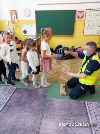 Policjant tłumaczący dzieciom zasady bezpieczeństwa