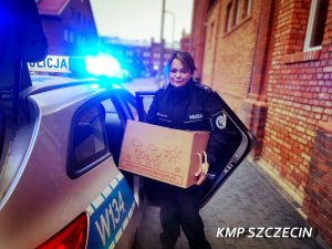 policjantka wkłada karton z prezentami do radiowozu