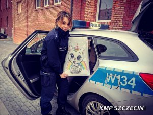policjantka wkłada karton z prezentami do radiowozu