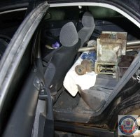 Otwarte tylne lewe drzwi od samochodu. W środku znajdują się metalowe elementy pochodzące z kradzieży.
