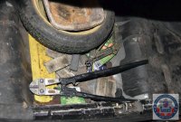 Bagażnik samochodu w którym znajduje się koło zapasowe oraz nożyce do ciącia metalu.