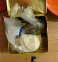 zdjęcie kolorowe na którym widać otwarte metalowe pudełko po herbacie z narkotykami zawiniętymi w folie
