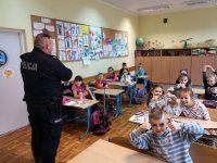 zdjęcie kolorowe na którym widać klasę z uczniami szkoły podstawowej oraz policjanta
