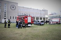zdjęcie kolorowe na którym widać grupę uczniów z liceum na boisku oraz liczne radiowozy służb mundurowych prezentujące sprzęt służbowy