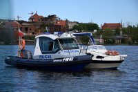 zdjęcie kolorowe na którym widać policyjną łódkę na wodzie oraz policjantów którzy patrolują teren wodny