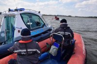 zdjęcie kolorowe na którym widać policyjną łódkę na wodzie oraz policjantów którzy patrolują teren wodny