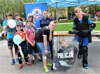 zdjęcie na którym widać festyn z udziałem policjantów i dzieci na jasnych błoniach