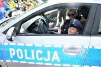 zdjęcie na którym widać siedzącego chłopca w radiowozie i uśmiechniętą policjantkę