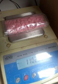 zdjęcie na którym widać różowe tabletki w woreczku foliowym które leża na wadze