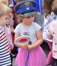 dziewczynka z czapce policyjnej i tarczą do zatrzymywania pojazdów