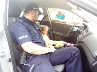 Policjant z dziewczynką w policyjnym radiowozie
