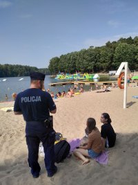 Policjant rozdający materiały profilaktyczne wypoczywającym na szczecińskich kąpieliskach