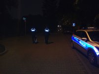 radiowóz policyjny nocą i patrolujący policjanci