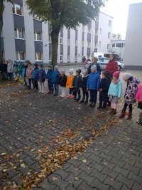Przedszkolaki z opiekunami przed budynkiem komisariatu
