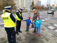 policjanci wręczają odblaski kobiecie z dziećmi