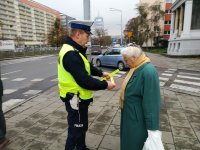 policjant wręcza odblask kobiecie starszej