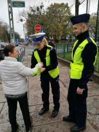 policjanci wręczają odblask kobiecie