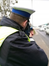 policjant mierzy prędkośći na drodze
