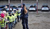 dzieci zwiedzają teren komendy policji na zdjęciu również policjantka