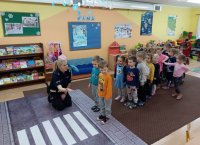 policjantka z dziećmi z przedszkola przeprowadza pogadankę