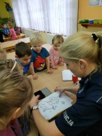 policjantka z dziećmi z przedszkola przeprowadza pogadankę