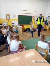 Policjant opowiadający dzieciom o zasadach bezpieczeństwa na drodze