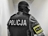Policjant kryminalny w kominiarce odwrócony plecami