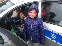 zdjęcie kolorowe na którym widać dzieci przy i w radiowozie policyjnym