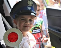Dziewczynka w czapce policyjnej, trzymająca tarczę do zatrzymywania pojazdów