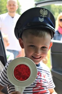Chłopiec w czapce policyjnej, trzymająca tarczę do zatrzymywania pojazdów