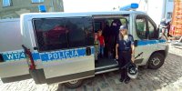 Policjantka prezentująca radiowóz najmłodszym uczestnikom festynu