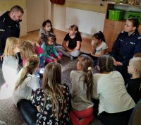dzieci i policjanci siedzą na podłodze