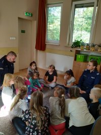 dzieci i policjanci siedzą na podłodze