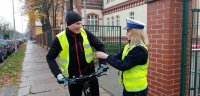 Policjantka wręczająca rowerzyście elementy odblaskowe