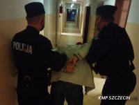 Policjanci prowadzą zatrzymanego mężczyznę w kajdankach